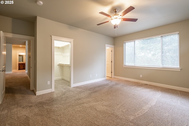 unfurnished bedroom with a spacious closet, baseboards, and light colored carpet