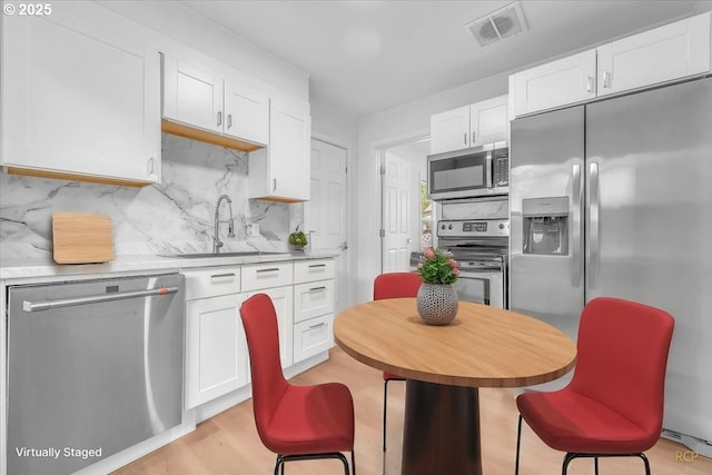 kitchen with visible vents, decorative backsplash, light countertops, white cabinets, and stainless steel appliances