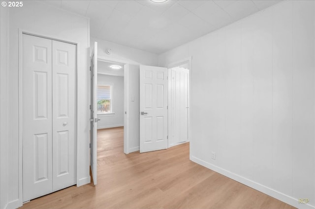unfurnished bedroom featuring baseboards, a closet, and light wood finished floors