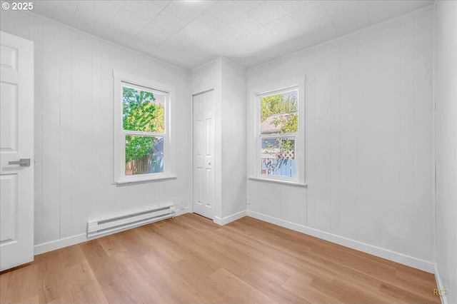 unfurnished room featuring light wood-style flooring, baseboard heating, and a healthy amount of sunlight