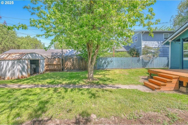 view of yard featuring a storage shed, a deck, fence, and an outbuilding