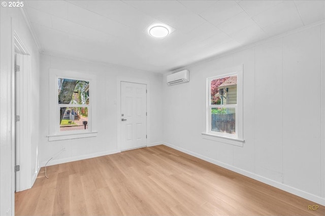 spare room with light wood-style floors, baseboards, crown molding, and a wall unit AC