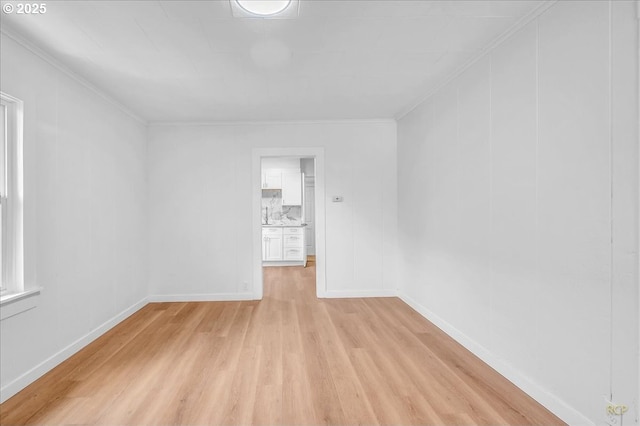 unfurnished room with baseboards, ornamental molding, and light wood finished floors