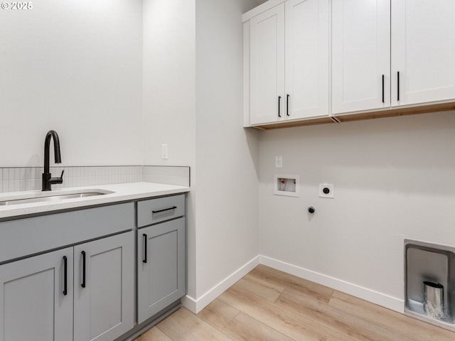 laundry area featuring sink, cabinets, washer hookup, hookup for an electric dryer, and light wood-type flooring