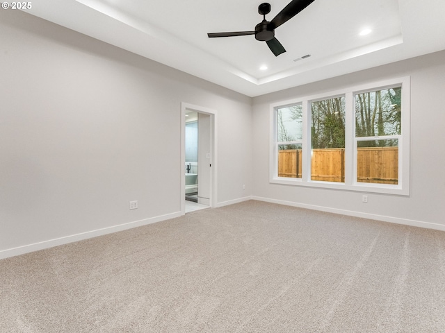 unfurnished room featuring a tray ceiling, carpet floors, and ceiling fan