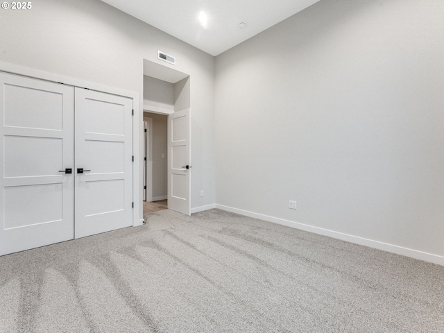 unfurnished bedroom with light colored carpet and a closet