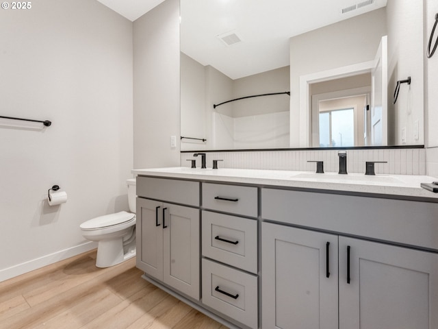 bathroom with toilet, a shower, wood-type flooring, vanity, and backsplash