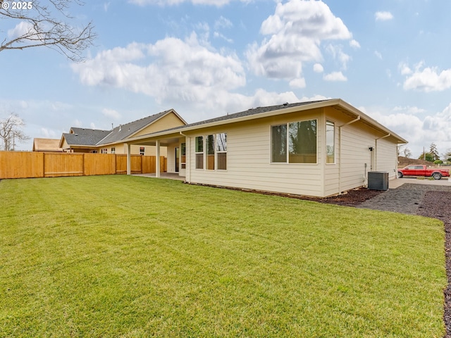 rear view of house featuring central air condition unit, fence, and a yard