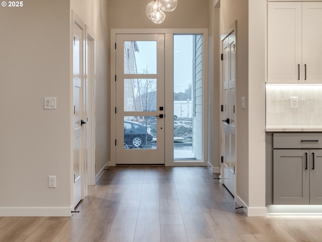 doorway to outside with french doors, baseboards, and light wood finished floors