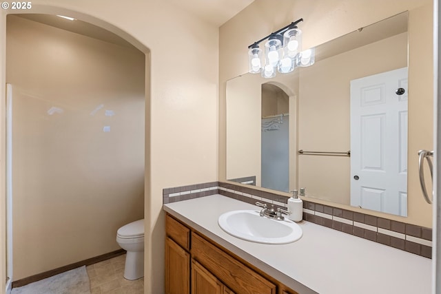 bathroom featuring toilet, vanity, and baseboards
