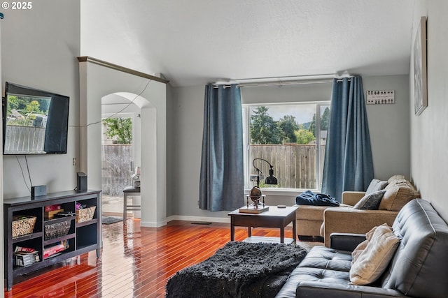 living area featuring arched walkways, wood finished floors, and baseboards