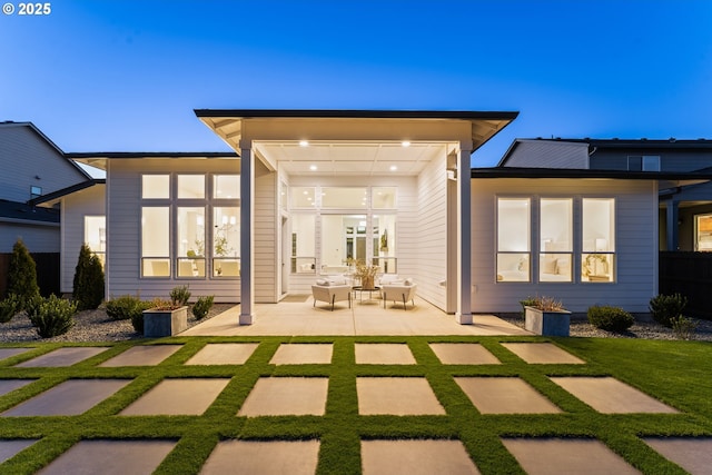 rear view of house with a patio and a lawn