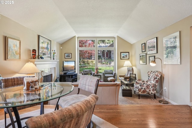 515 SW Colony Dr, Portland, OR 97219 - living area with wood finished floors, a fireplace, vaulted ceiling, a textured ceiling, and baseboards