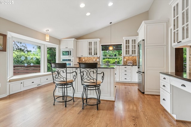 515 SW Colony Dr, Portland, OR 97219 - kitchen with appliances with stainless steel finishes, dark countertops, a kitchen bar, decorative backsplash, and vaulted ceiling