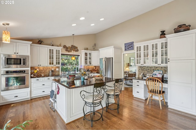 515 SW Colony Dr, Portland, OR 97219 - kitchen with appliances with stainless steel finishes, dark countertops, lofted ceiling, a kitchen breakfast bar, and tasteful backsplash