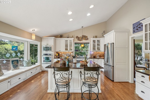 515 SW Colony Dr, Portland, OR 97219 - kitchen featuring stainless steel appliances, dark countertops, vaulted ceiling, tasteful backsplash, and white cabinets