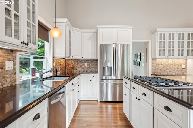 515 SW Colony Dr, Portland, OR 97219 - kitchen featuring appliances with stainless steel finishes, backsplash, white cabinets, and decorative light fixtures