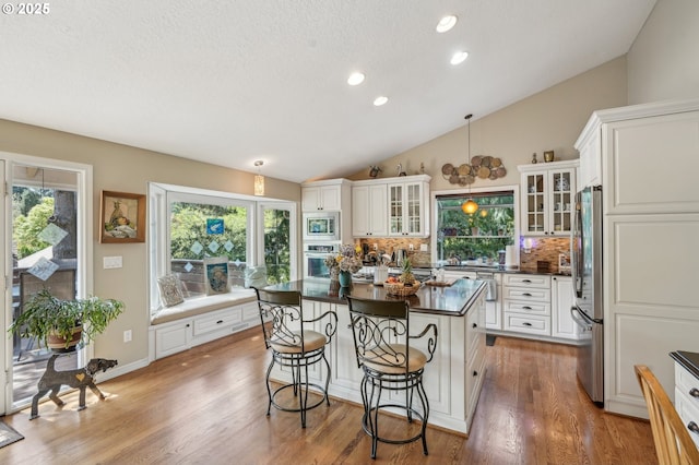 515 SW Colony Dr, Portland, OR 97219 - kitchen featuring stainless steel appliances, dark countertops, decorative backsplash, white cabinetry, and vaulted ceiling