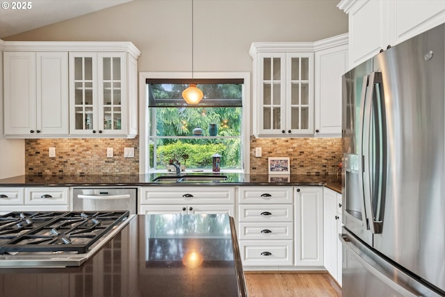 515 SW Colony Dr, Portland, OR 97219 - kitchen with appliances with stainless steel finishes, dark countertops, white cabinets, backsplash, and vaulted ceiling