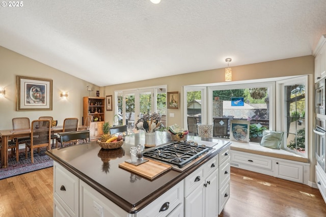 515 SW Colony Dr, Portland, OR 97219 - kitchen featuring appliances with stainless steel finishes, light wood finished floors, a textured ceiling, vaulted ceiling, and a kitchen island