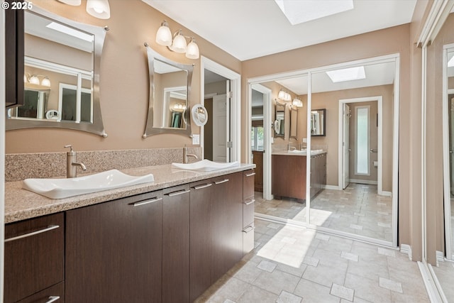 515 SW Colony Dr, Portland, OR 97219 - full bathroom featuring a skylight, double vanity, and baseboards