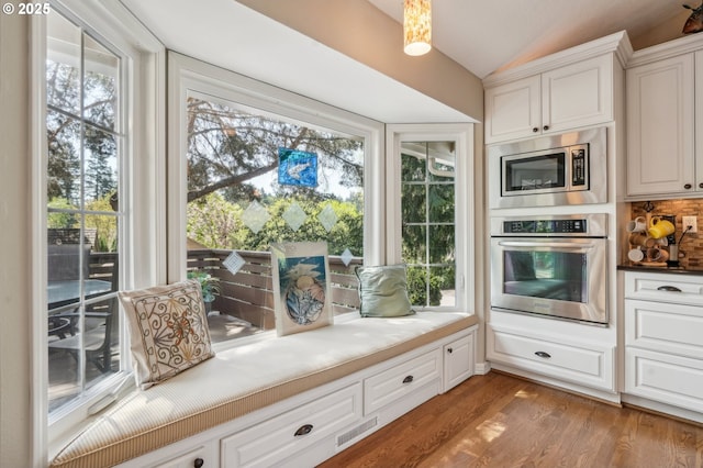 515 SW Colony Dr, Portland, OR 97219 - kitchen featuring stainless steel appliances, lofted ceiling, white cabinets, wood finished floors, and tasteful backsplash