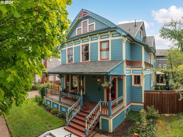 victorian house featuring a porch and a front lawn