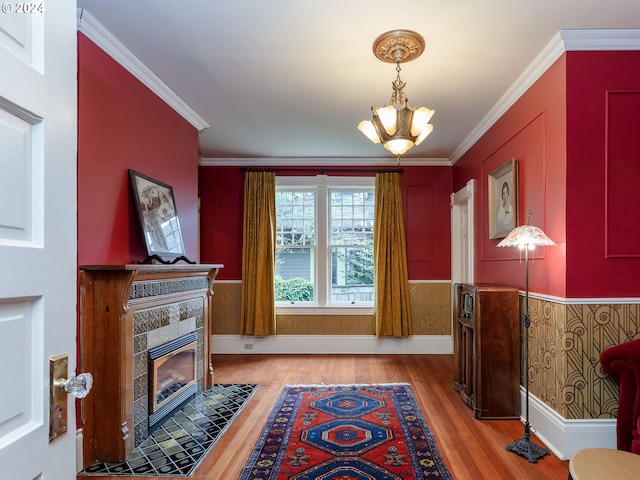 foyer entrance with a notable chandelier, ornamental molding, a tile fireplace, and light hardwood / wood-style flooring