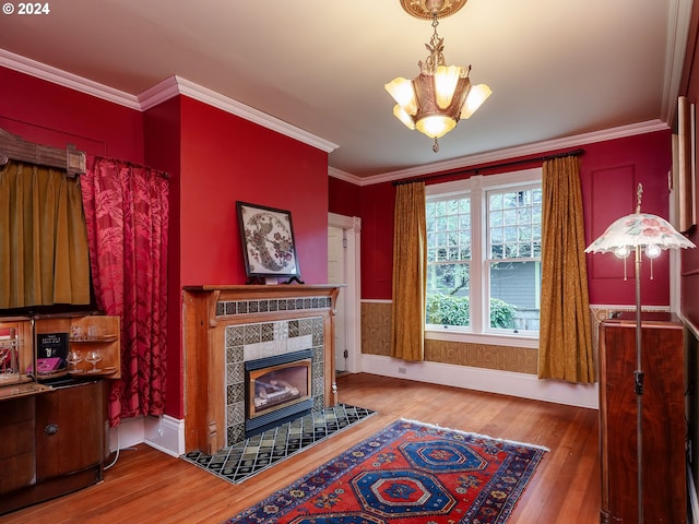 living room with crown molding, a chandelier, a tiled fireplace, and hardwood / wood-style flooring