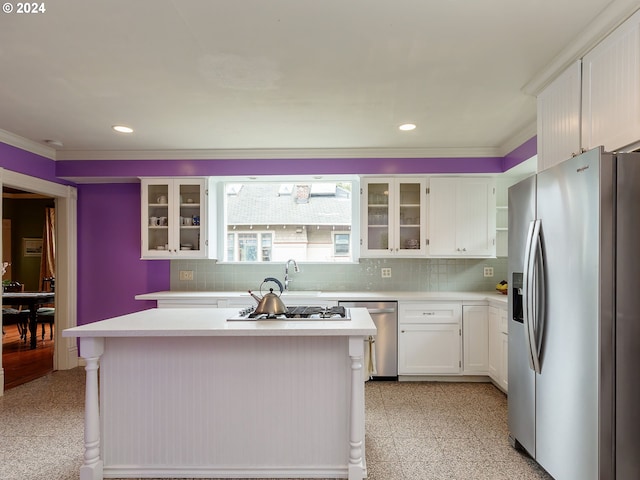 kitchen featuring stainless steel appliances, white cabinetry, a center island, and tasteful backsplash