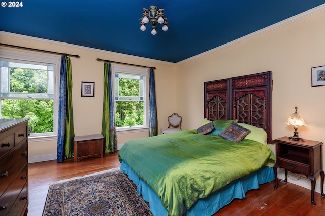 bedroom featuring multiple windows, hardwood / wood-style floors, and ornamental molding