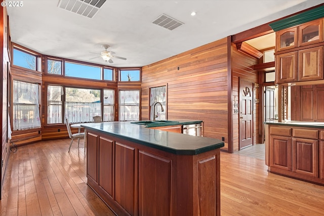 155 N 6th Ave, Elgin, OR 97827 - kitchen with dark countertops, ceiling fan, light wood-style floors, a sink, and wood walls