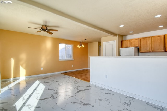 interior space featuring hanging light fixtures, ceiling fan with notable chandelier, stainless steel fridge, and a textured ceiling