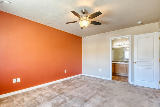 unfurnished bedroom with ensuite bathroom, light carpet, ceiling fan, and a textured ceiling