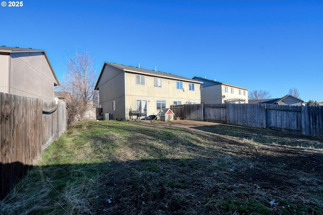 rear view of house featuring central AC and a yard