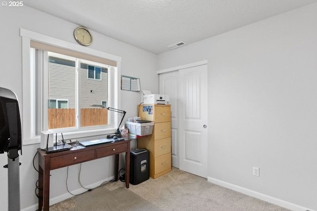 office space featuring light carpet, visible vents, baseboards, and a textured ceiling