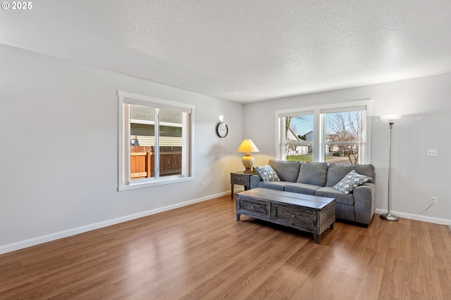 living room with a textured ceiling, baseboards, and wood finished floors