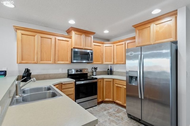 kitchen featuring stainless steel appliances, light brown cabinetry, a sink, and recessed lighting