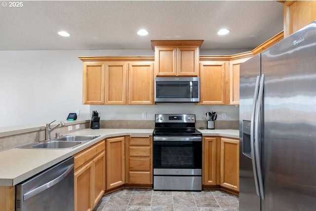 kitchen featuring a peninsula, stainless steel appliances, light countertops, a sink, and recessed lighting