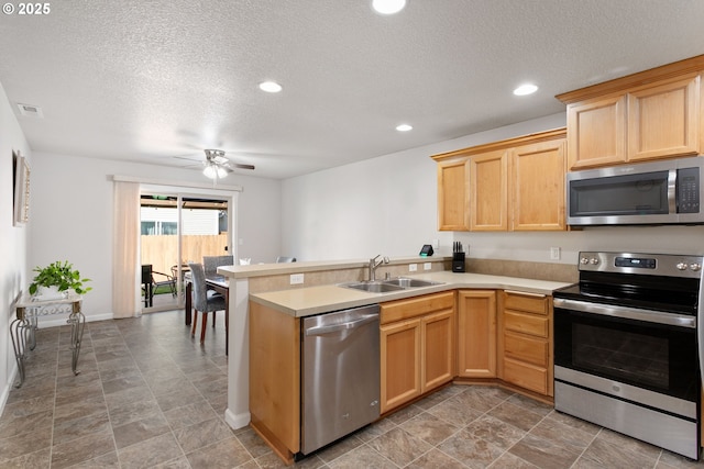 kitchen with a peninsula, a sink, visible vents, light countertops, and appliances with stainless steel finishes