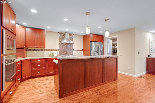 17616 SW Ivy Glenn Dr, Beaverton, OR 97007 - kitchen with stainless steel appliances, wall chimney range hood, light wood-style floors, a kitchen island, and recessed lighting