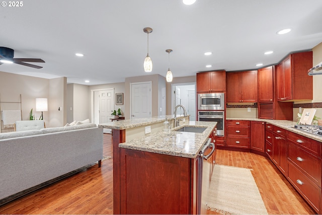 17616 SW Ivy Glenn Dr, Beaverton, OR 97007 - kitchen featuring stainless steel appliances, light wood-type flooring, a ceiling fan, a kitchen island with sink, and pendant lighting