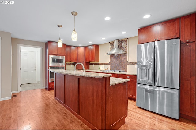 17616 SW Ivy Glenn Dr, Beaverton, OR 97007 - kitchen featuring stainless steel appliances, wall chimney exhaust hood, light wood finished floors, decorative backsplash, and recessed lighting