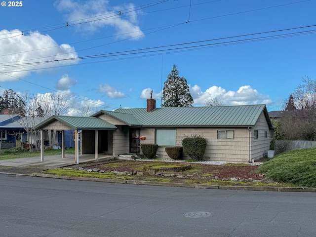 ranch-style house featuring a standing seam roof, metal roof, a chimney, and fence