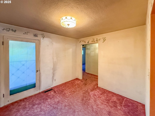 carpeted spare room featuring visible vents and a textured ceiling