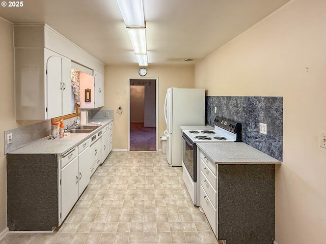 kitchen featuring white cabinets, electric stove, freestanding refrigerator, light countertops, and a sink