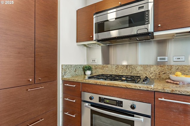 kitchen with appliances with stainless steel finishes, light stone counters, and brown cabinets