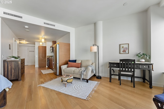 living room featuring baseboards, visible vents, and light wood finished floors