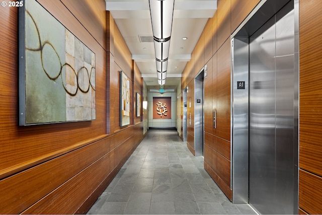 hallway with elevator, wooden walls, and visible vents