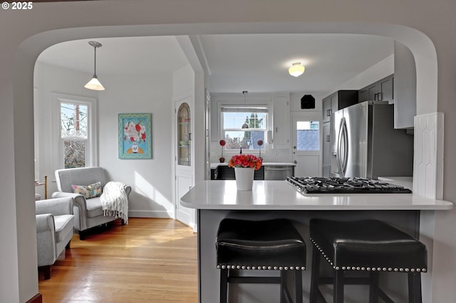 kitchen featuring stainless steel fridge, light wood-style flooring, light countertops, and gas stovetop